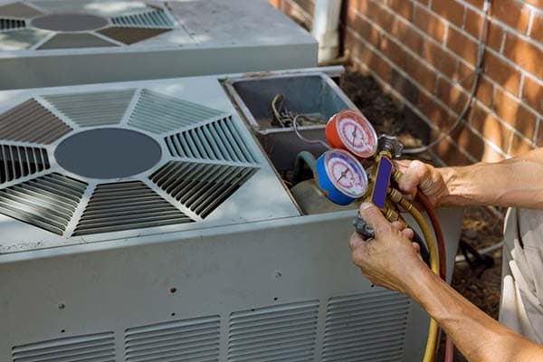 HVAC technician checking refrigerant levels on an outdoor condenser unit