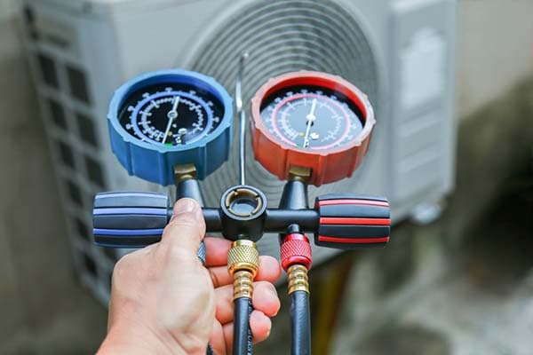 Technician holding manifold gauges during an HVAC tune-up