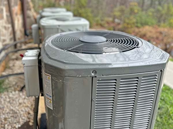 Row of outdoor HVAC condenser units installed at a new construction site